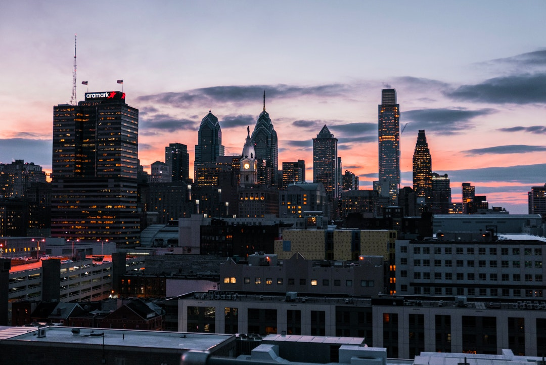 City skyline at sunset with illuminated skyscrapers.